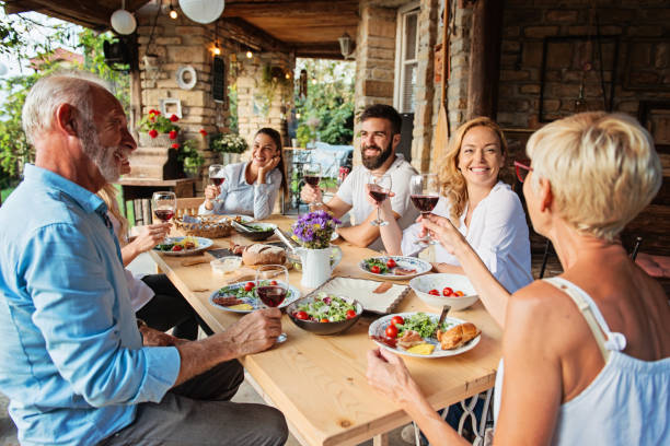 Family and friends enjoying an Italian meal outdoors with wine and fresh food.