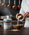 Person pouring rice from a wooden bowl into another bowl with Acquerello rice canister in a kitchen setting.