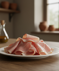 Sliced ham on a white plate with a blurred kitchen background
