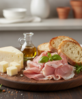Platter of sliced prosciutto, cheese, and bread with a small bottle of olive oil on a wooden board.