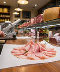 Sliced ham on a wooden counter with a deli setting in the background