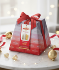 Bonifanti Pandoro packaging with a red ribbon on a marble surface with Christmas decorations.