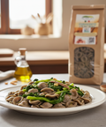 Plate of pasta with greens on a table with a package in the background