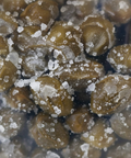 Close-up of green peppercorns with salt crystals on a dark background