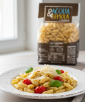 Pasta dish with tomatoes and basil on a plate, Acqua & Terra pasta package in the background.