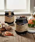 Jars of cuttlefish ink on a wooden table with seafood ingredients.