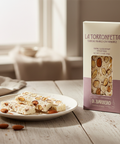 Torrone on a plate with a box of La Torronfetta D. Barbero on a wooden table.