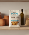 Bag of Rummo Rigatoni No. 50 gluten-free pasta on a wooden shelf with rustic decor.