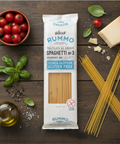 Rummo gluten-free spaghetti package on a wooden surface with ingredients like tomatoes, basil, and olive oil.