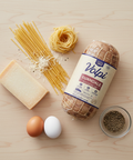 Volpi guanciale packaging with spaghetti, cheese, eggs, and herbs on a wooden surface