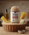 Basket with Volpi guanciale, spaghetti, and olive oil on a wooden surface.