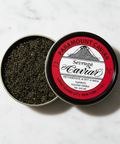 Open container of caviar with a red label on a white marble surface