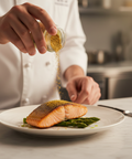 Person seasoning salmon on a plate with a sprinkle of spice in a kitchen setting