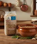 Bag of Del Colle Italian Zollino Beans on a wooden surface with a terracotta pot filled with beans.