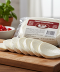 Sliced mozzarella cheese on a wooden board with a package of mozzarella in the background.