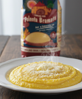 Steaming polenta on a plate with a can of Polenta Bramata in the background.