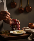 Person opening a jar of Calippo tomato sauce with a spoon on a rustic setting.