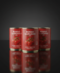 Three cans of Rosso Gargano cherry tomatoes on a reflective surface with a dark background
