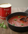Can of Rosso Garofalo tomatoes next to a skillet with tomato sauce and basil leaves on a wooden surface.