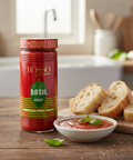 Red sauce jar labeled 'Rosso Garganega' with a bowl of tomato sauce and bread on a wooden table.