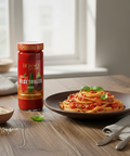 Spaghetti dish with a jar of Rosso Pomodoro D'Uovo sauce on a wooden table.