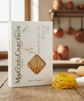 Marcozzi di Campofilone pasta box on a wooden surface with pasta strands and kitchen background