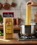 Pasta being added to a pot with Pastai Gragnanesi packaging on a kitchen counter.