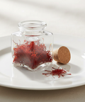 Clear glass jar with saffron on a white plate
