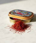 Open tin of saffron threads on a light surface