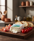 Wooden cutting board with cheese, tomatoes, and cured meat in a kitchen setting
