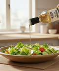 Person pouring olive oil over a salad in a kitchen setting