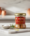 Jar of Callipo yellowfin tuna fillets in olive oil on a marble surface with a blurred kitchen background.